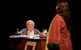 Simon Russell Beale (60s) is sat behind a harpsicord which has papers, wine, and a glass atop it. He's wearing an embroidered waist coat and looks startled.