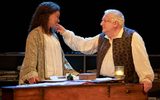 Racheal Ofori and Simon Russell Beale are stood behind the harpsicord. They're looking at each other and his hand is touching her cheek.