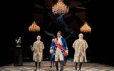 3 chandeliers hang above the scene. Pravessh Rana leads a formation of guards. Pravessh is wearing a regal blue suit jacket and a red sash. His guards are in beige attire.