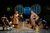 BoD 2-013 The cast of The Book of Dust on stage, there are wooden tables and chairs with cast sitting in a busy pub.