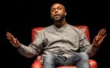 Nwosu Leo sits on a red leather armchair and gestures as he speaks