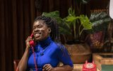 Faith Omole holds the receiver of a bright red landline phone