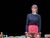 Sthbry-073 Jo Herbert stands looking bemused in a long sleeved top and red skirt.
