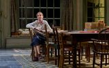 Phoebe Nicholls sits at wooden table with her hands clasped and looks sad.