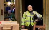 Holly Atkins stands in a doorway wearing a high vis jacket and carrying a motorbike helmet.