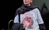 Hermione Gulliford stands, she is in conversation and wears a large white t shirt with a photo of young girl on it, it reads 'Justice for Taylor'.